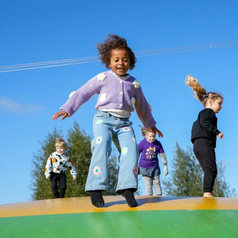 Young girl bouncing on a bouncy pillow - outdoor fun at the farm park